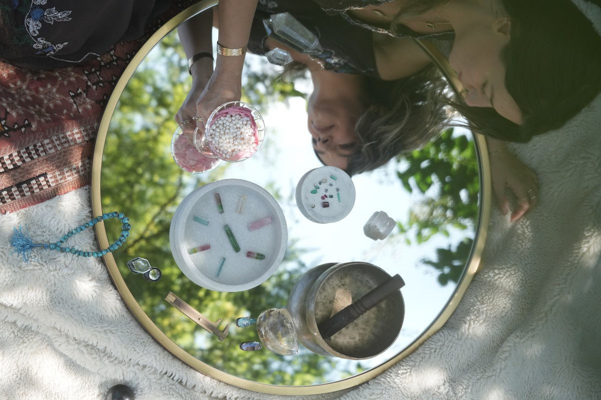Tourmaline, pearls, a loupe and a caliper laid out on a round mirror at the Albisia jewelry studio in Tampa