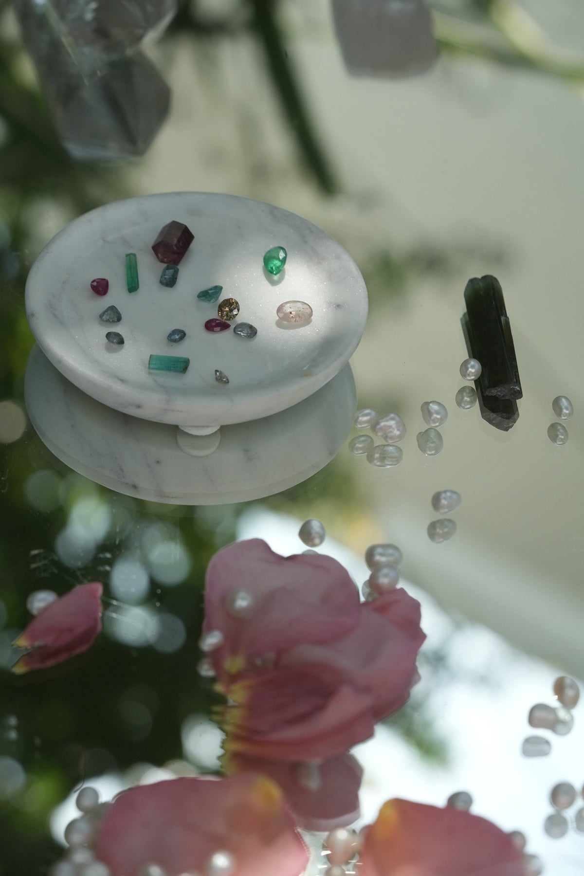 Loose emeralds, rubies and sapphires in a marble dish before setting, Albisia fine jewelry Tampa