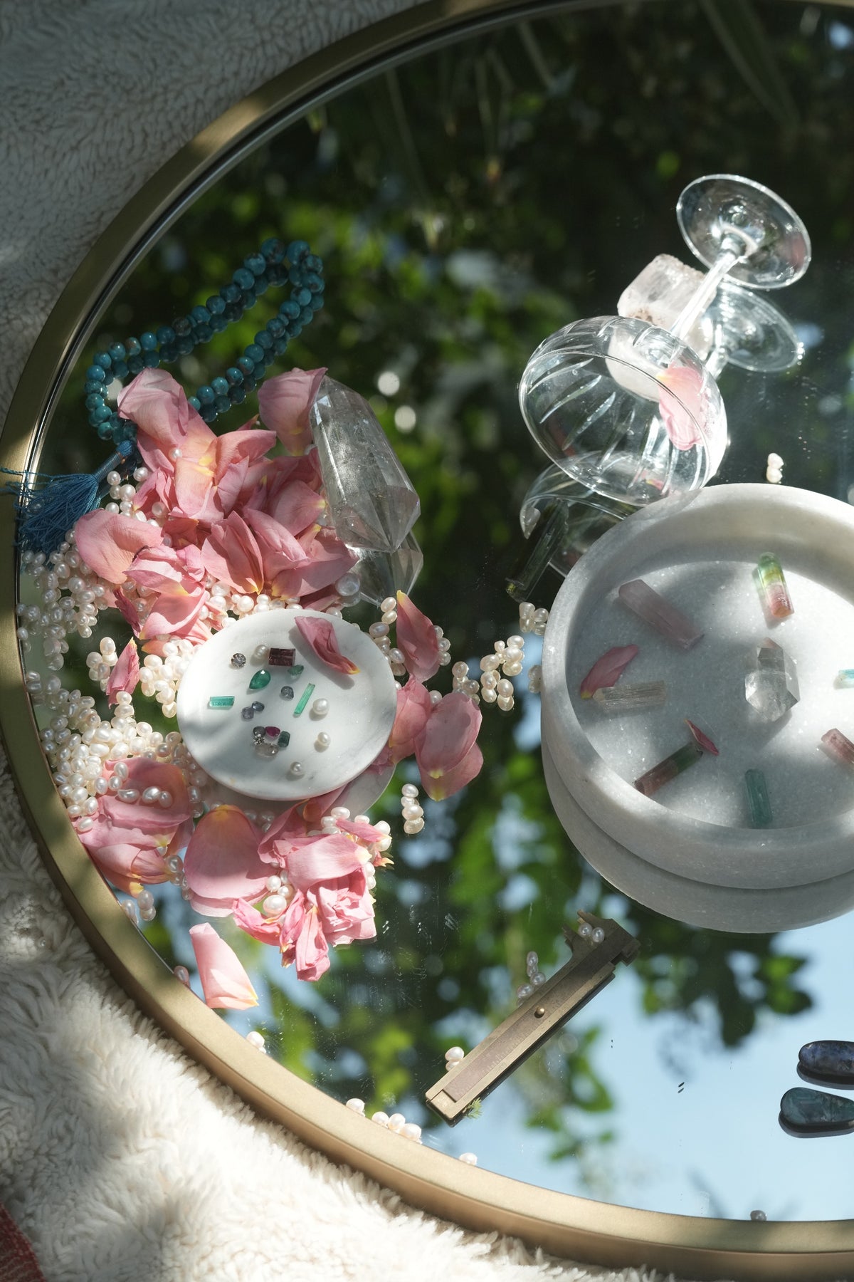 Rose petals, loose freshwater pearls, raw tourmaline and a brass caliper on a mirror, materials for handmade Albisia jewelry